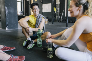 A group of exercise enthusiasts sitting down for a break and a drink between exercise routines.