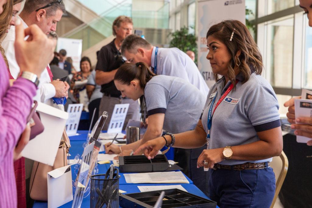 U.S. Postal Service members sell stamps to attendees of the first-day-of-issue ceremony at the Annenberg Presidential Conference Center.