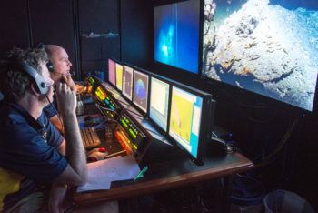 Scott Sofolofsky (background) and GISR PI Chip Breier (foreground) work in the ROV control room on the E/V Nautilus