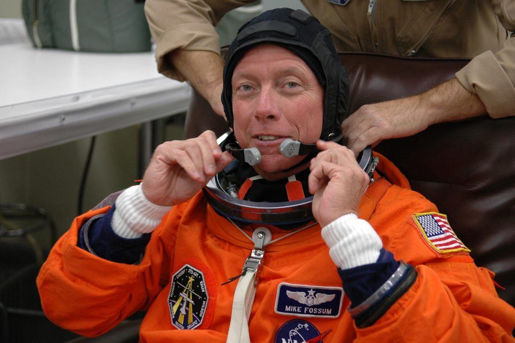 Michael Fossum is helped with his launch suit
