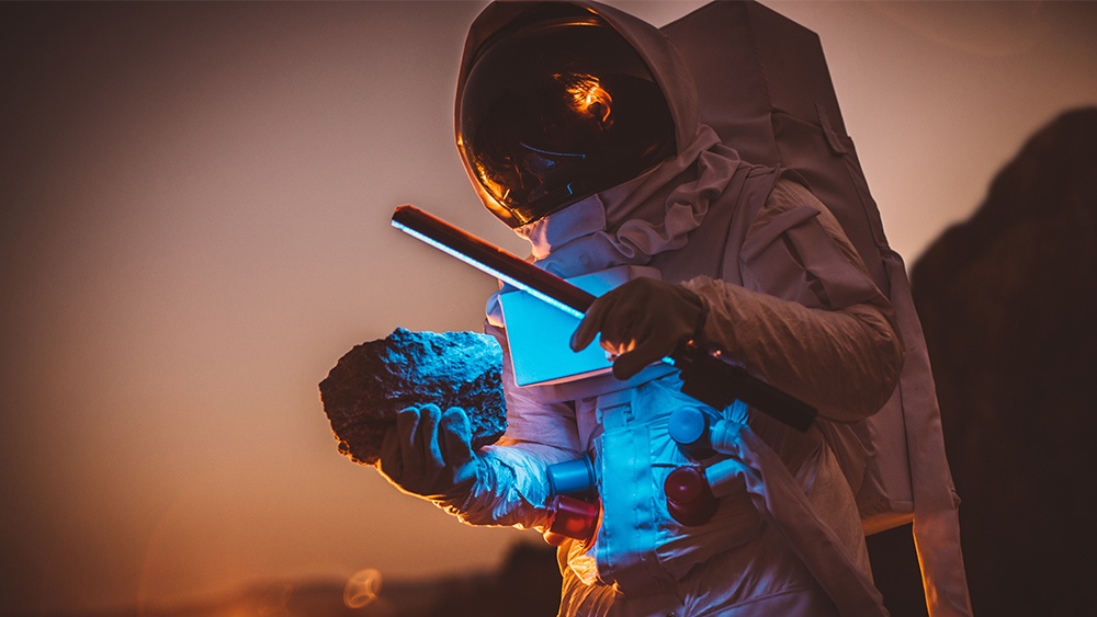 Astronaut waving blue light over a rock