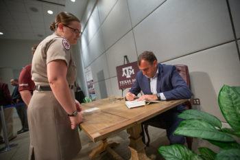 Author Alex Kershaw sits at a table as he signs a student's book
