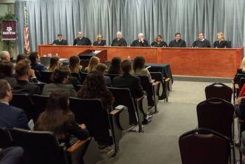 Justices of the Supreme Court of Texas speak to an auditorium of guests.