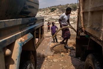 Men fill trucks with water from a nearly dried up riverbed on February 24, 2017 in Dhudo, Somalia