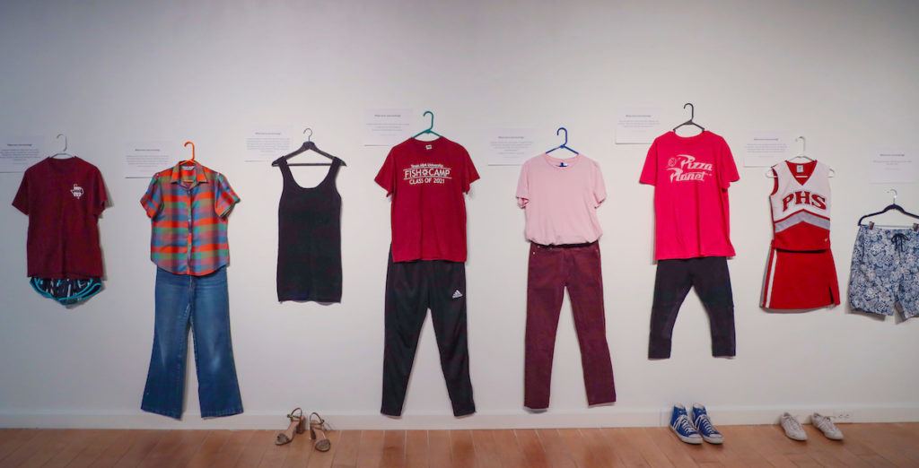 several outfits hang on a white wall