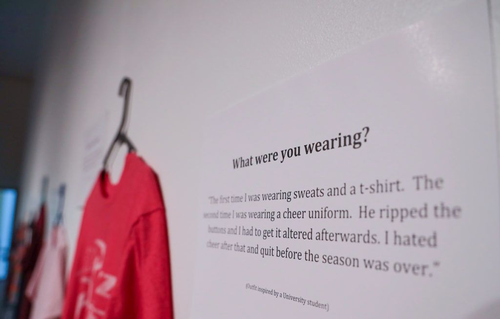 A placard with a story from a sexual assault survivor next to a red t-shirt