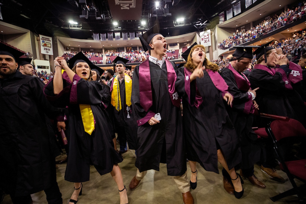 students wearing caps and gowns celebrating at graduation