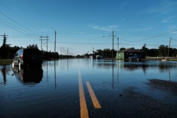 An abandoned car sits in high water along a street