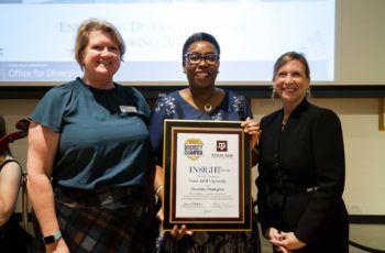Three women pose with an award