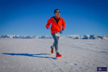 A student wearing a red jacket runs across the snow in Antarctica