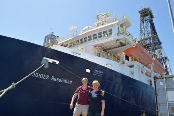 Two woman stand in front of a ship