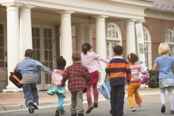 Rear view of young students running to building