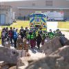 an ambulance and crowd of people in first responder outfits in front of earthquake rubble
