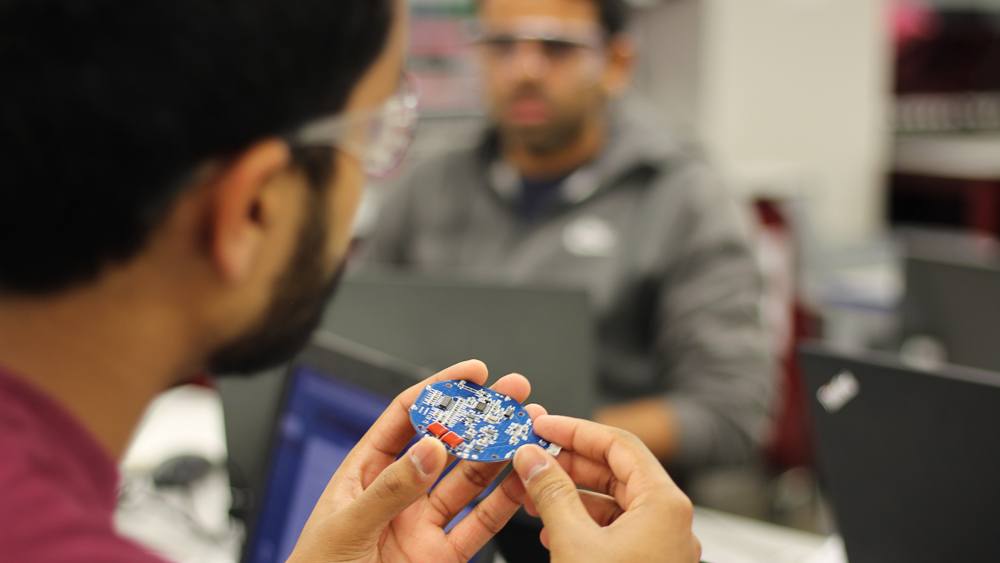close-up view of a student wearing safety goggles holding a piece of technology