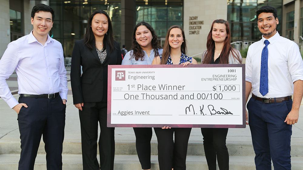 students standing in a row holding an oversized check for $1,000