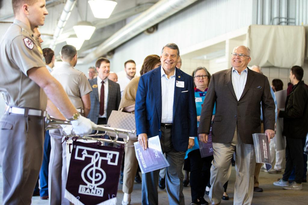 donors walk through the hall of champions past cadets with trumpets