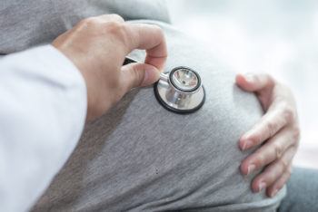 Doctor checking pregnant woman with stethoscope