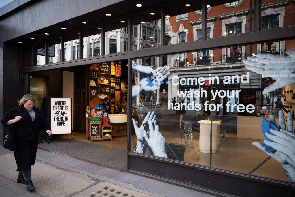 a woman walks past a story advertising a free hand-washing facility