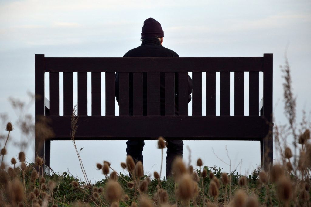a man sits alone on a park bench