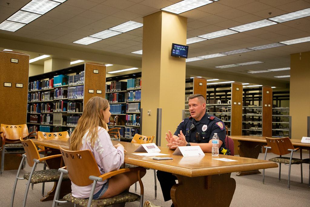 A woman sitting across from a University Police Officer having a conversation.