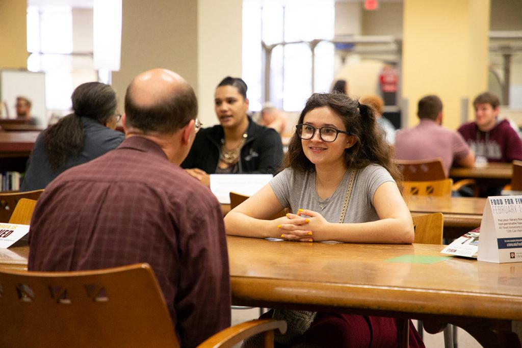 A man and woman sitting across a table from one another having a conversation