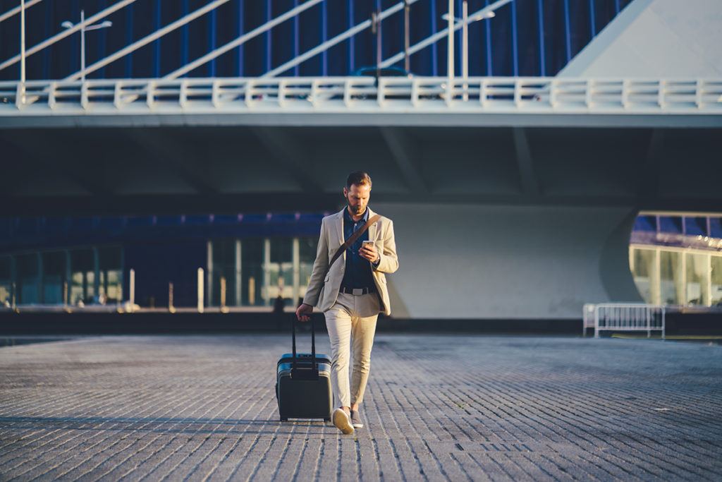 a traveler in Spain toting a suitcase and looking at his phone