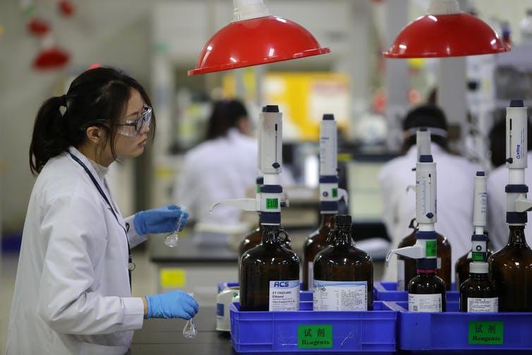 woman in white coat and goggles working in a pharmaceutical center