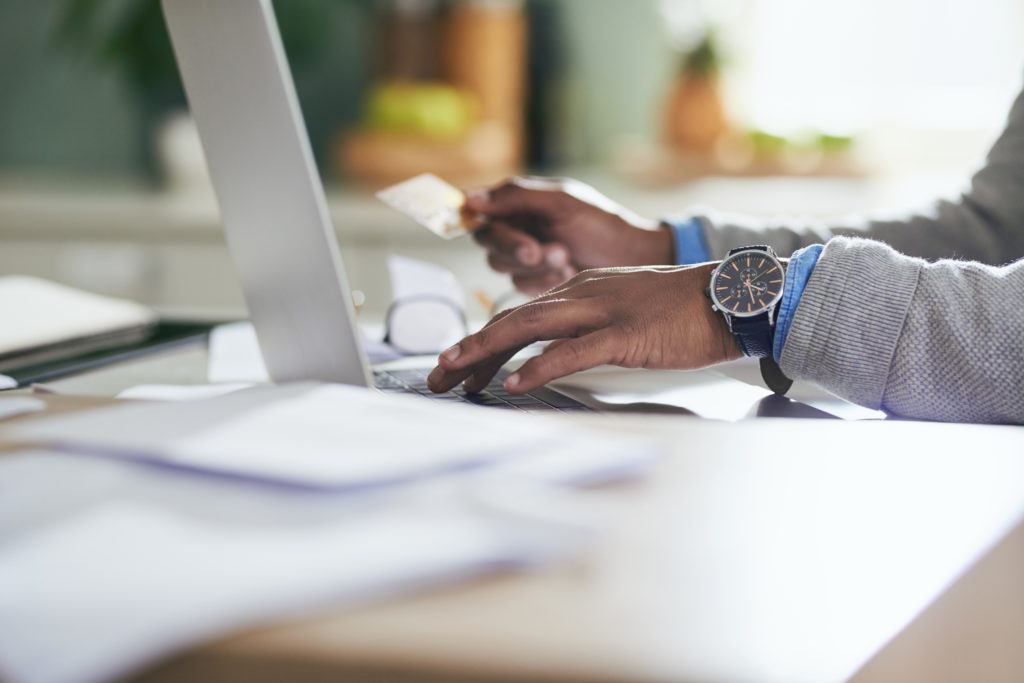 Closeup shot of an man using a credit card and laptop at home