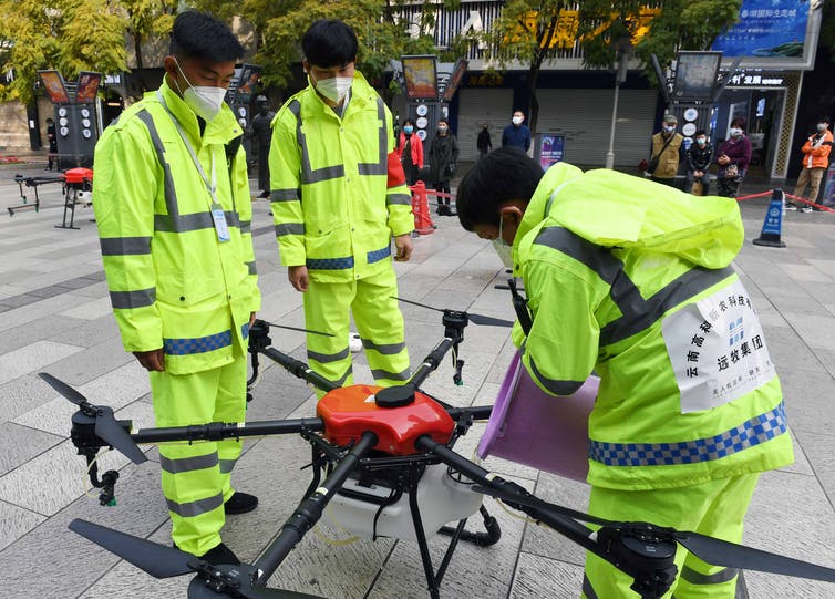 Workers in Kunming City, Yunnan Province, China refill a drone with disinfectant. The city is using drones to spray disinfectant in some public areas.