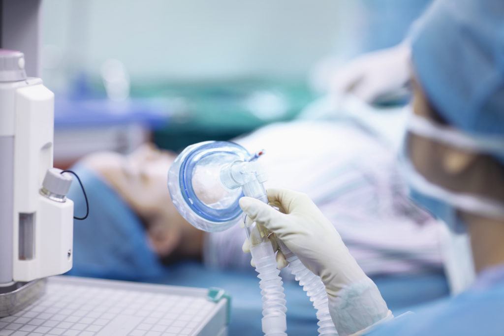 Nurse holding anesthesia mask in operating room