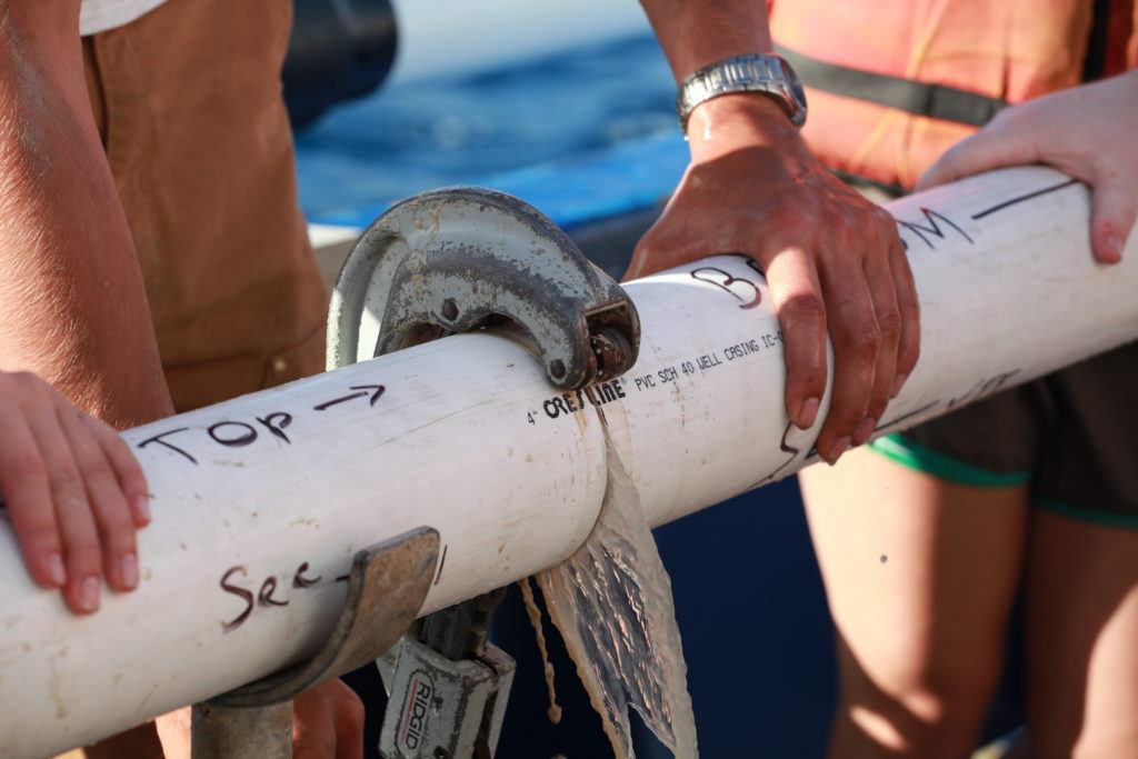 hands holding sediment core on boat