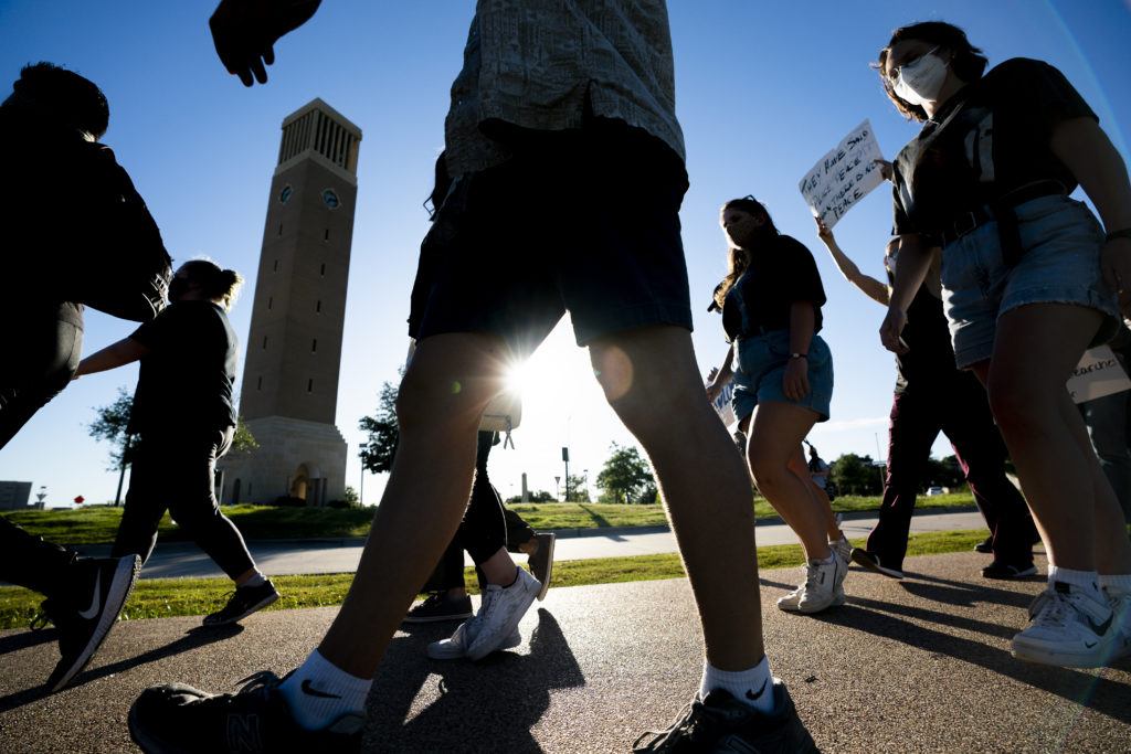 people backlight by the sun walking in front of the albritton clock tower