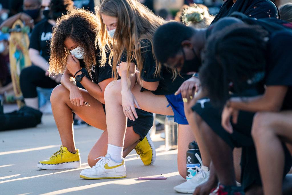 close up image of studnets kneeling with heads bent