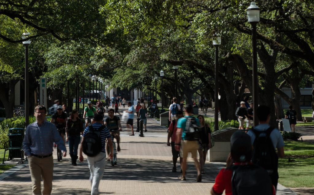 students walking in shaded area of campus between campus