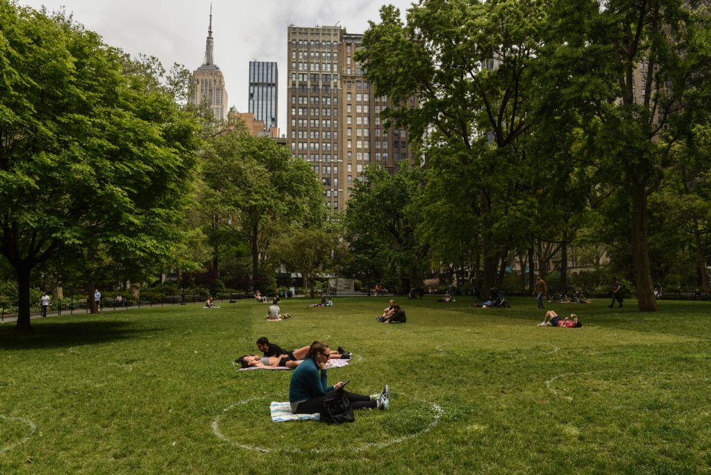people sit in white painted circles on the grass in a park