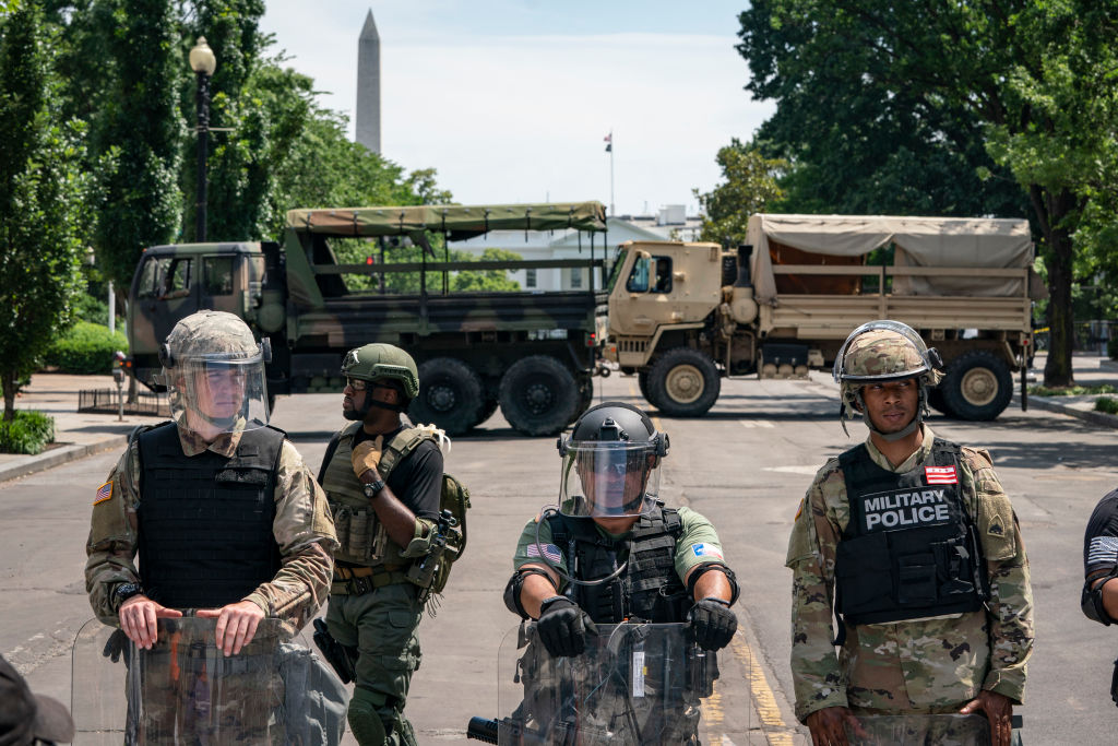 police officers and national guard vehicles block a street with the white house in the background