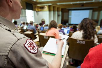 image from behind of a cadet taking notes in a teaching theatre among other students