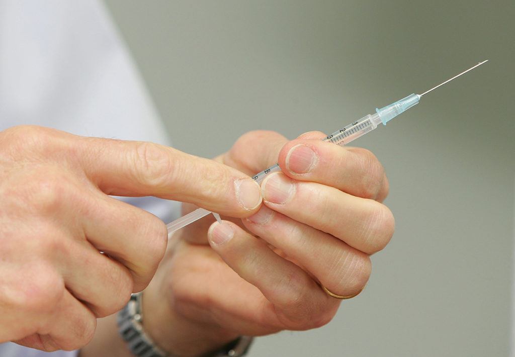 a photo of a man's hands holding a hypodermic needle