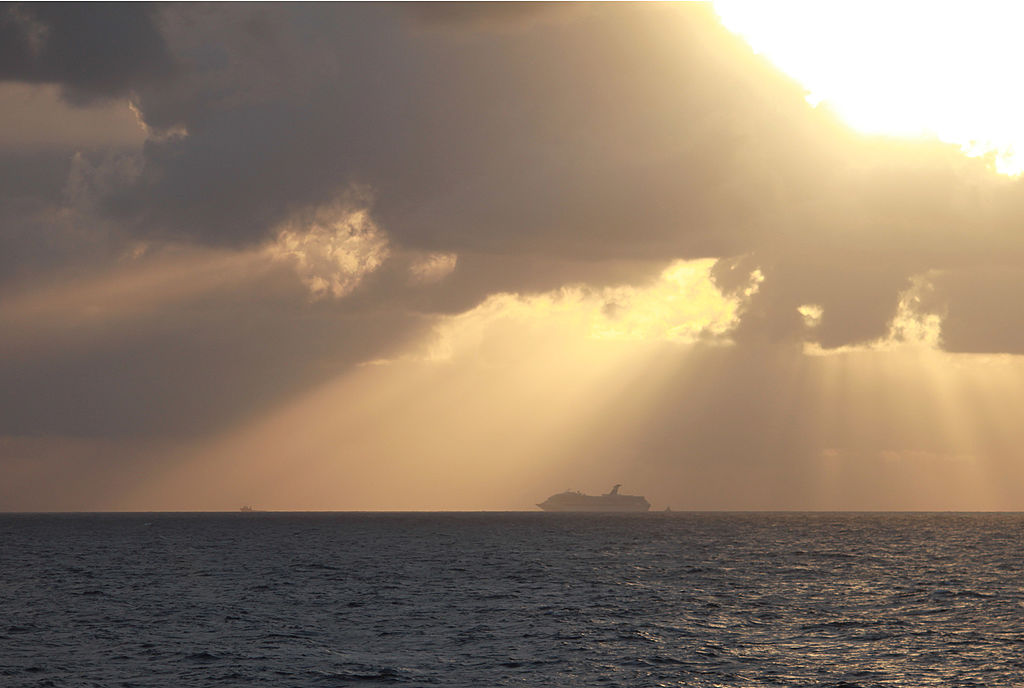 a boat in the distance on the gulf of mexico against a sunset