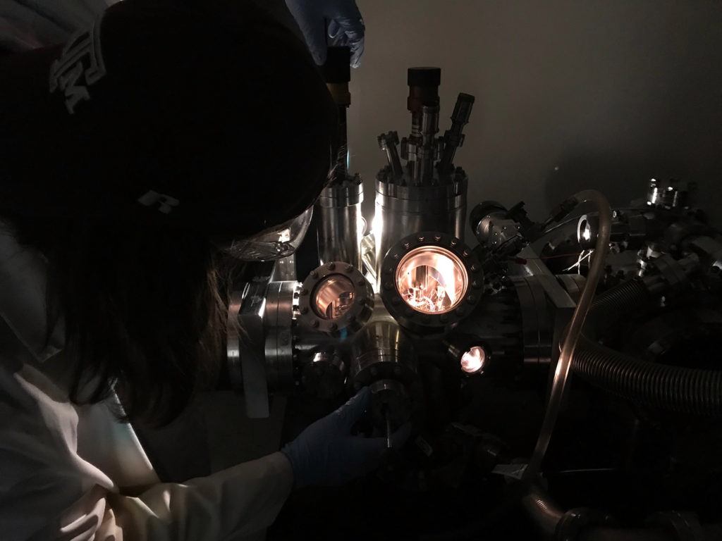 dark image of a student bending over a microscope