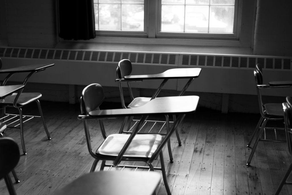 black and white photo of empty desks in a classroom