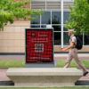 a photo of a student walking by a digital Howdy bubly sign