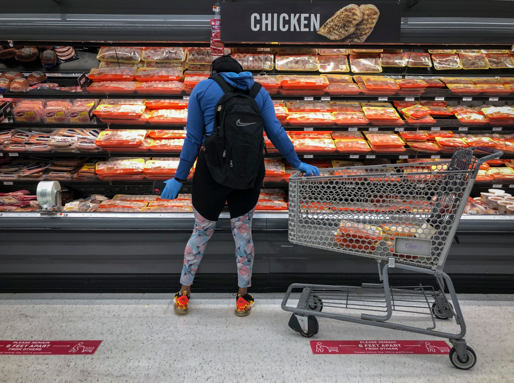 woman shopping in meat and chicken aisle of grocery store