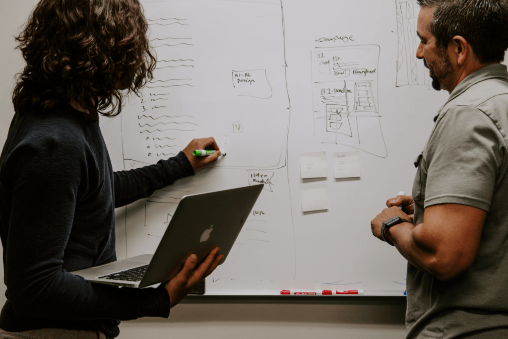 two people standing at a whiteboard talking