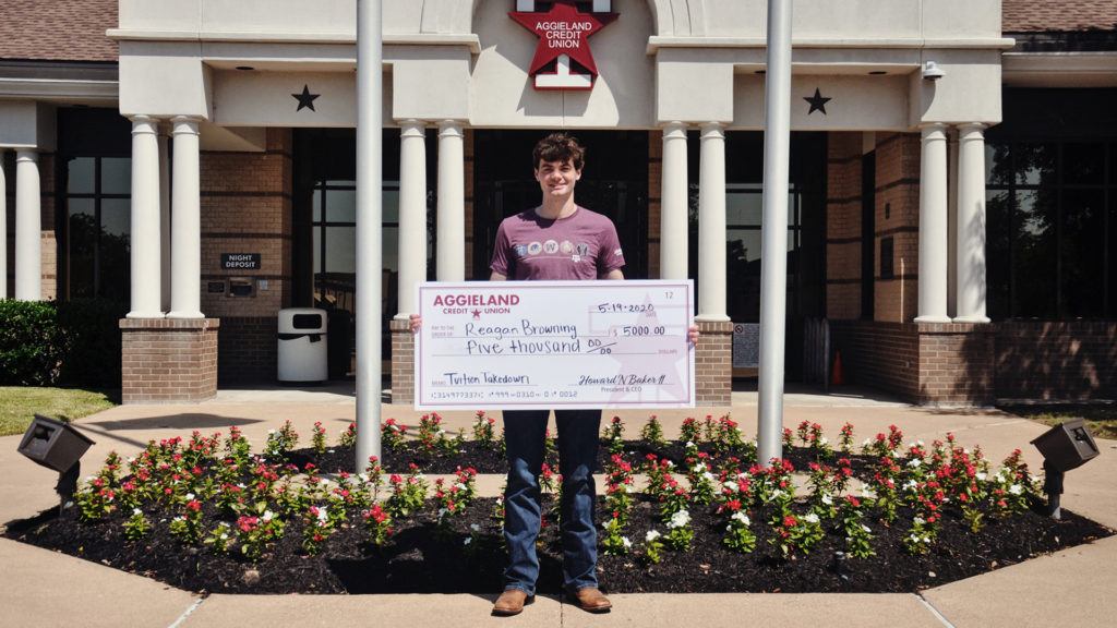 student standing outside with a large check
