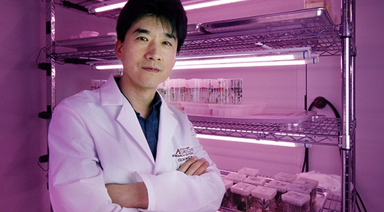 portrait of professor in white coat standing in a lab with purple lighting