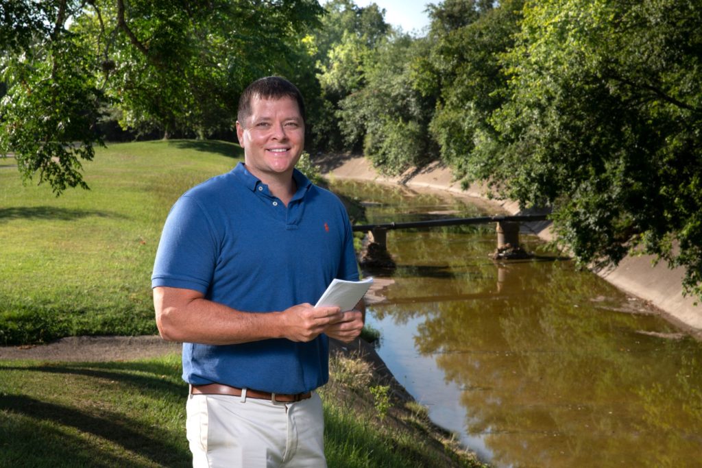portrait of galen newman outside next to a drainage ditch filled with water