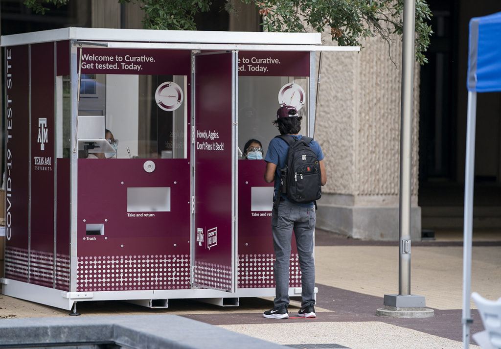 a student standing in front of a COVID-19 testing kiosk on campus