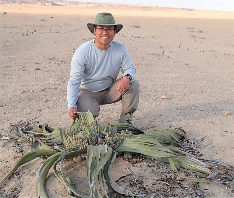 professor kneeling in desert