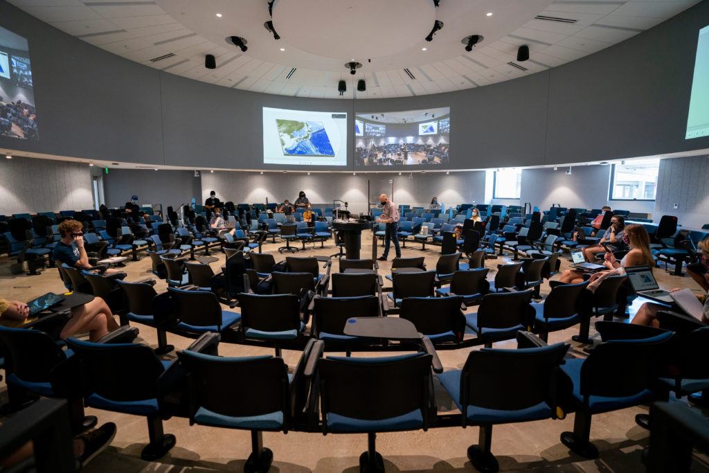 students sit in round lecture hall